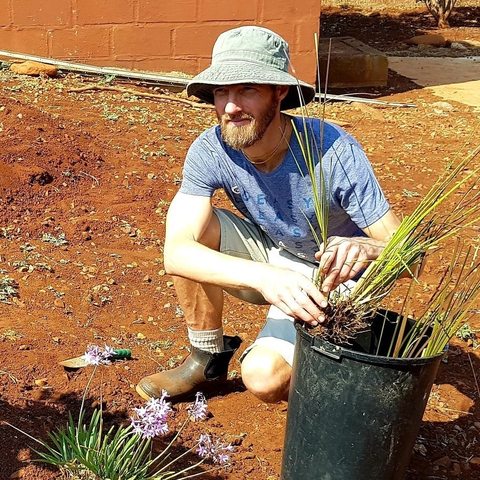Rory Clark preparing rooted plants from a bucket beside the garden at Ubhejane Crèche